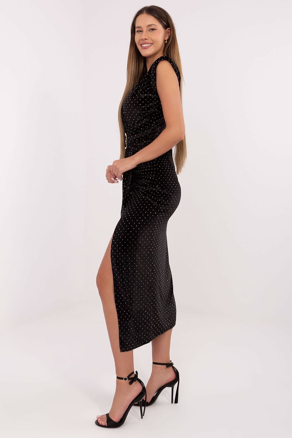 Woman wearing a black polka dot dress with a side slit on a white background