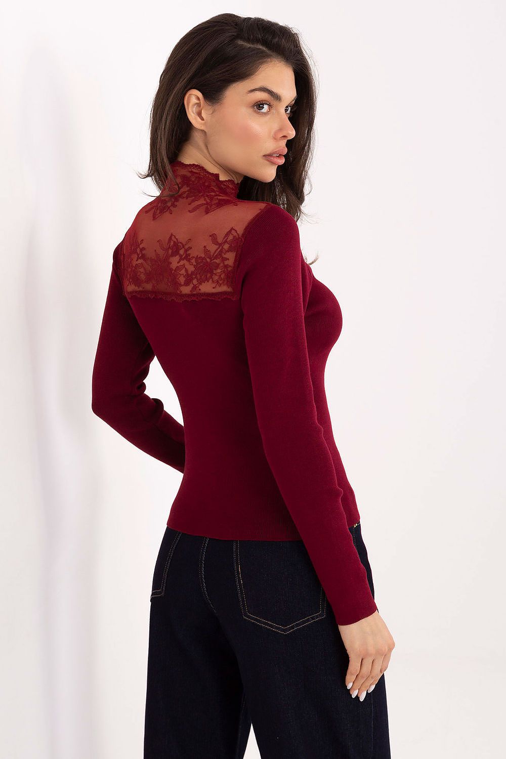 Woman wearing a burgundy long-sleeve top with lace detailing on a white background