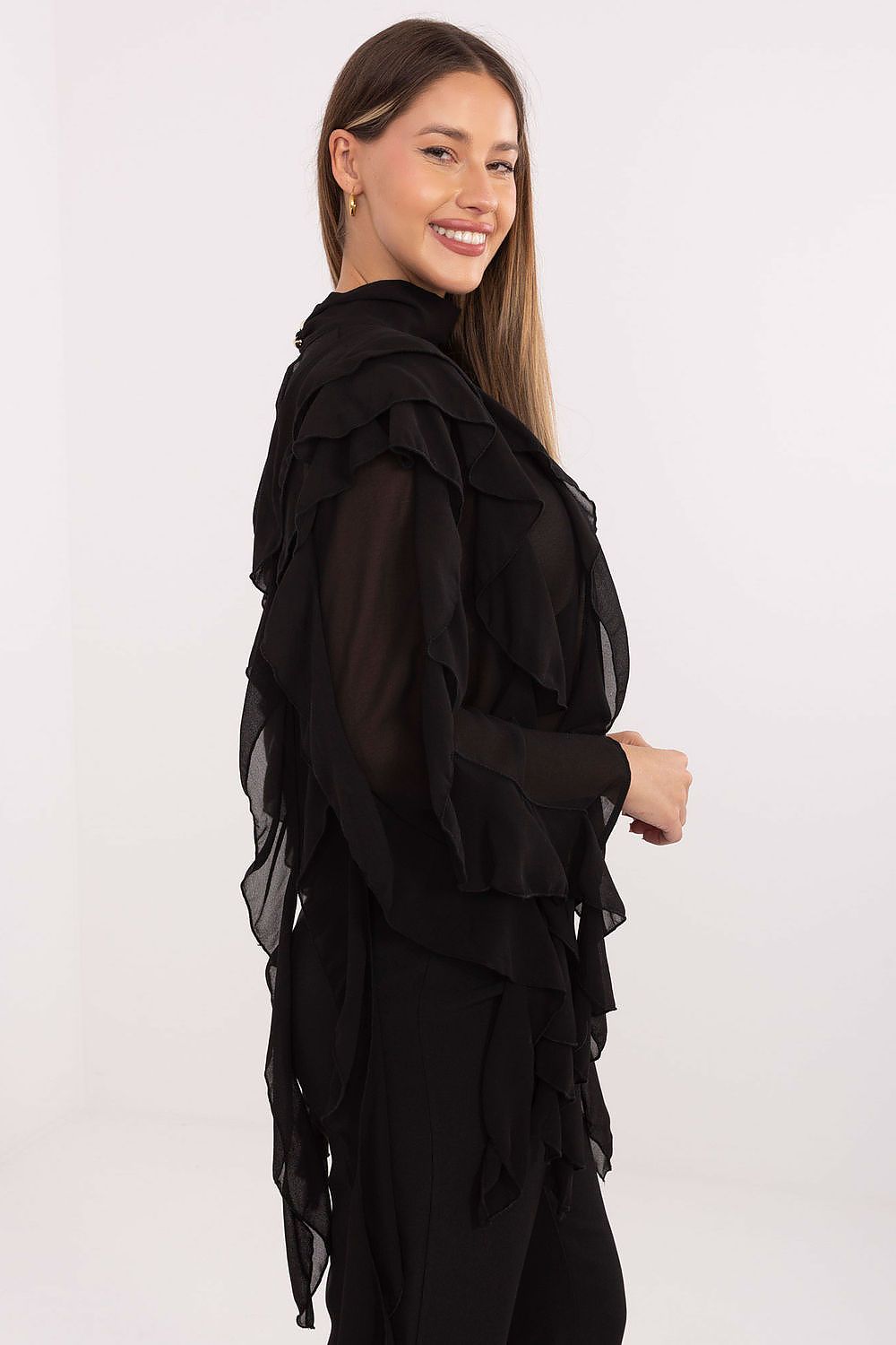 Woman wearing a black ruffled top against a white background