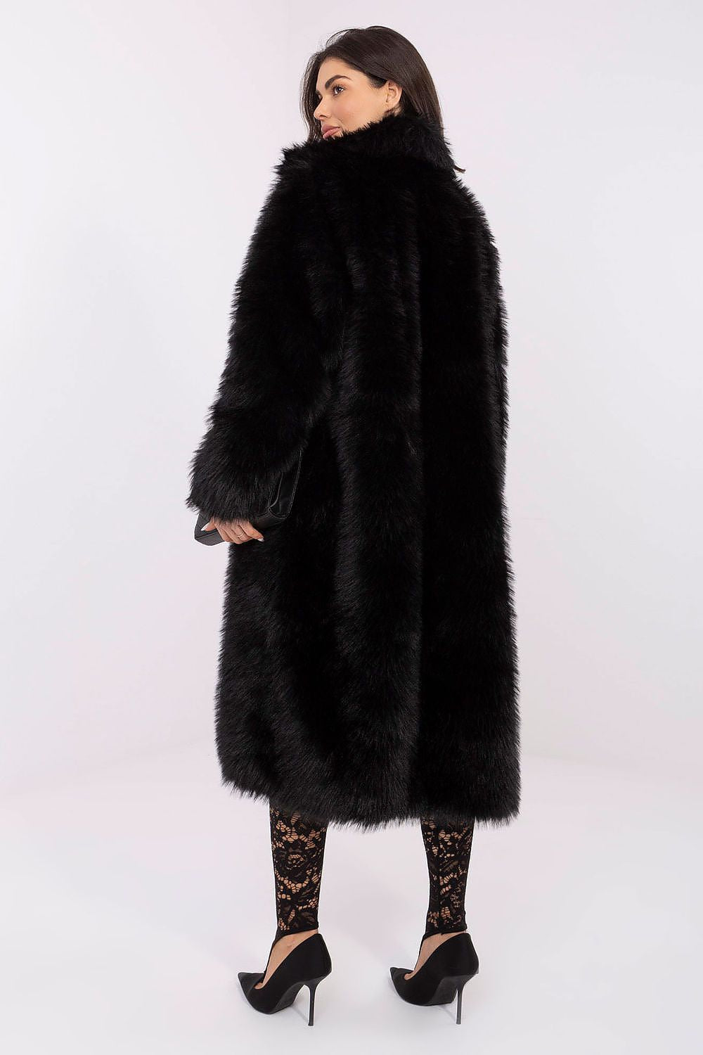 Woman wearing a long black fur coat on a white background