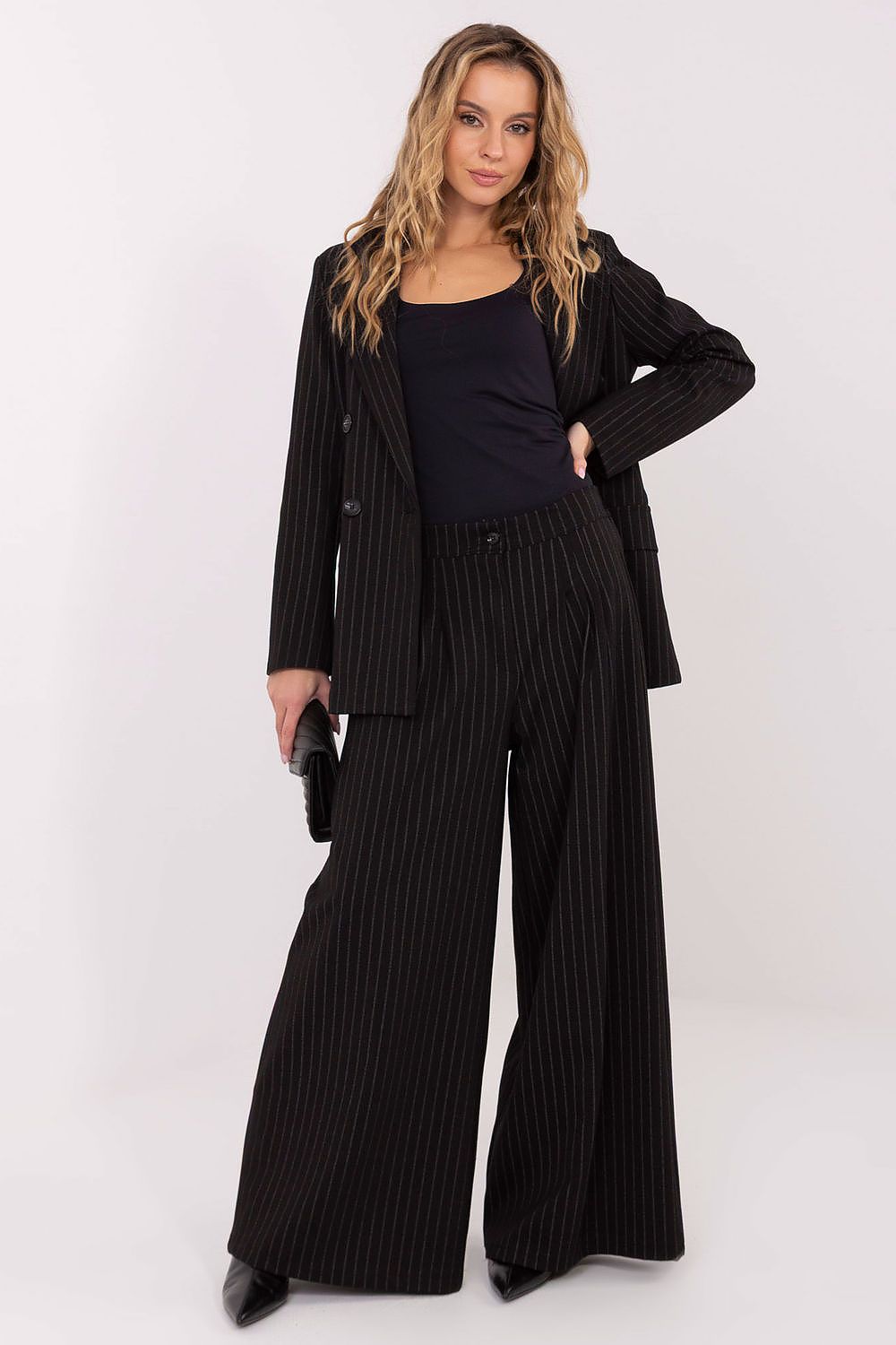 Woman wearing a black suit with wide-leg pants on a white background