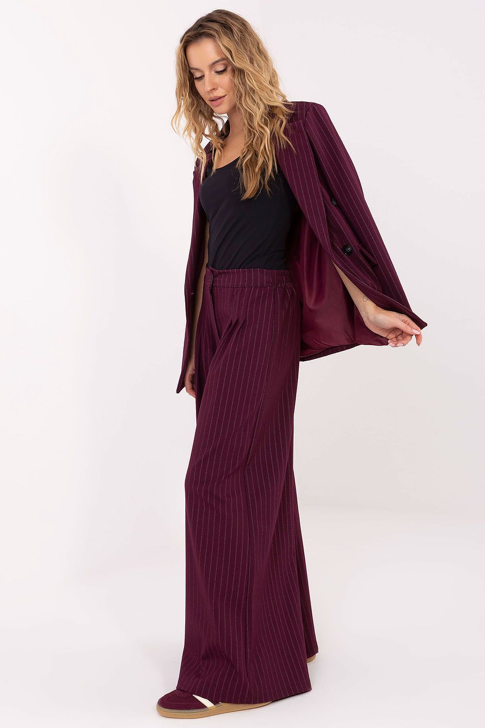 Woman wearing a burgundy blazer and pants on a white background