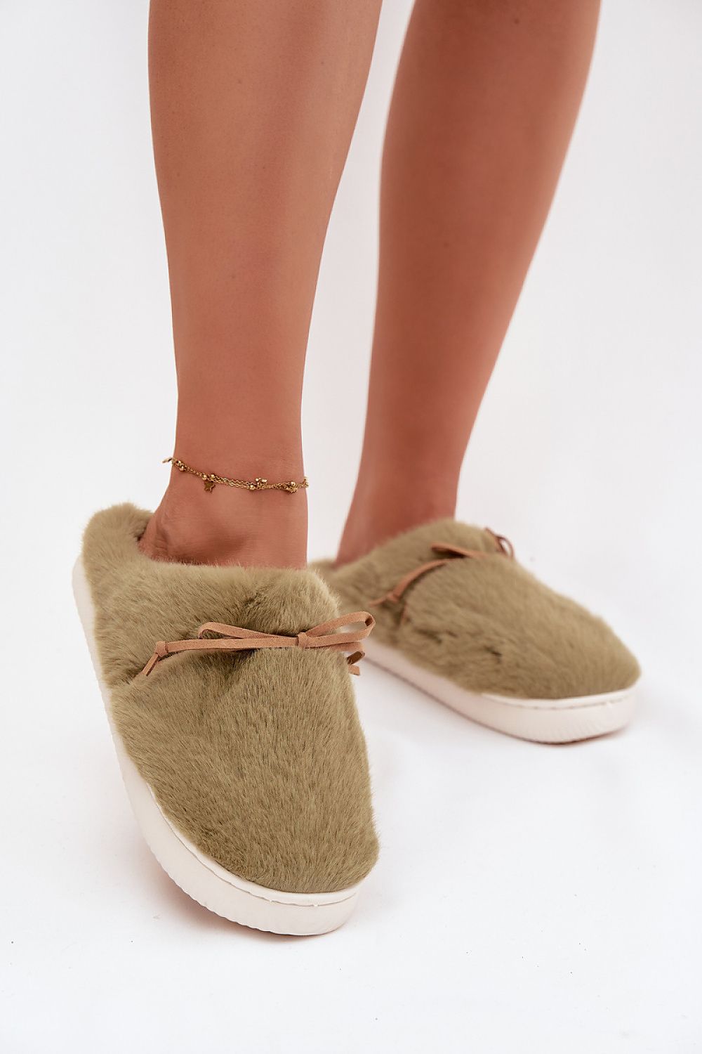 Green slippers worn with beige tights on a white background