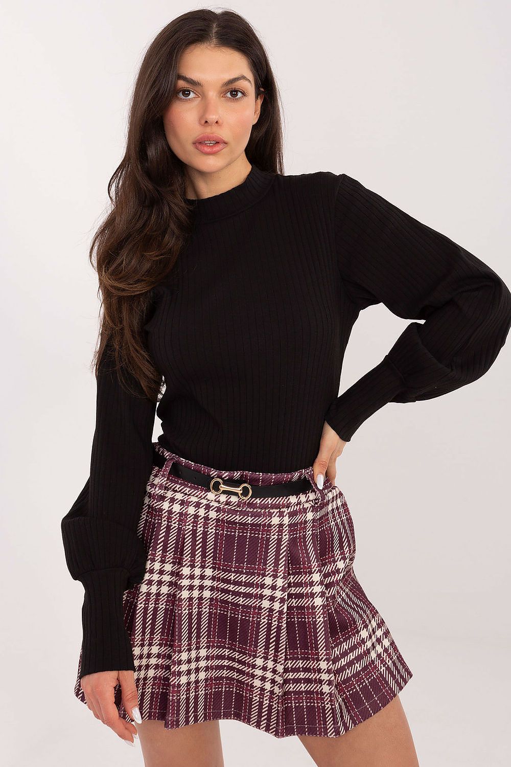 Woman wearing a black sweater and plaid skirt on a white background