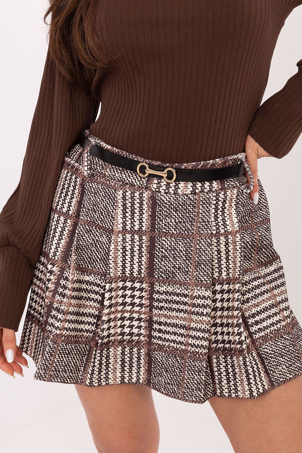 Person wearing a brown ribbed sweater and plaid skirt on a white background