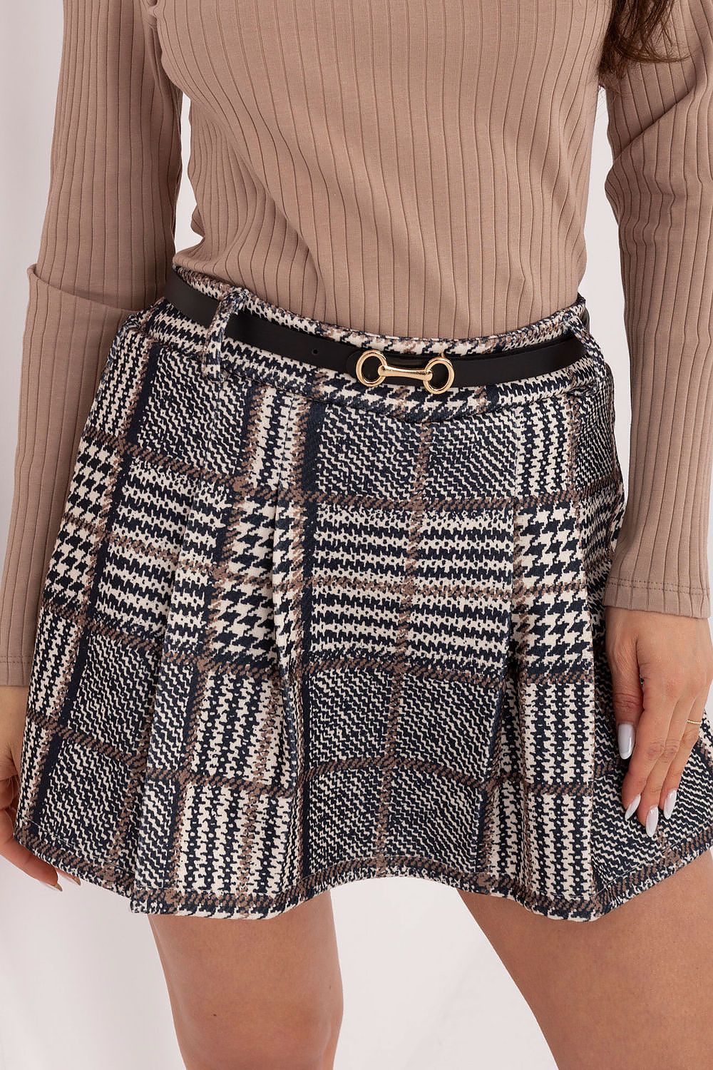 Plaid skirt with a gold buckle worn by a person in a beige ribbed sweater on a white background