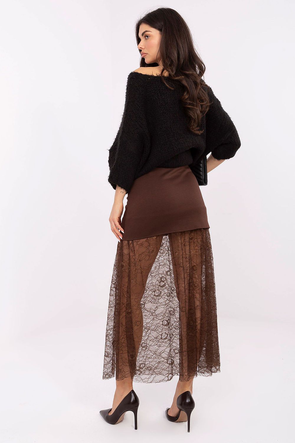 Woman wearing a black top and brown skirt with lace overlay on a white background