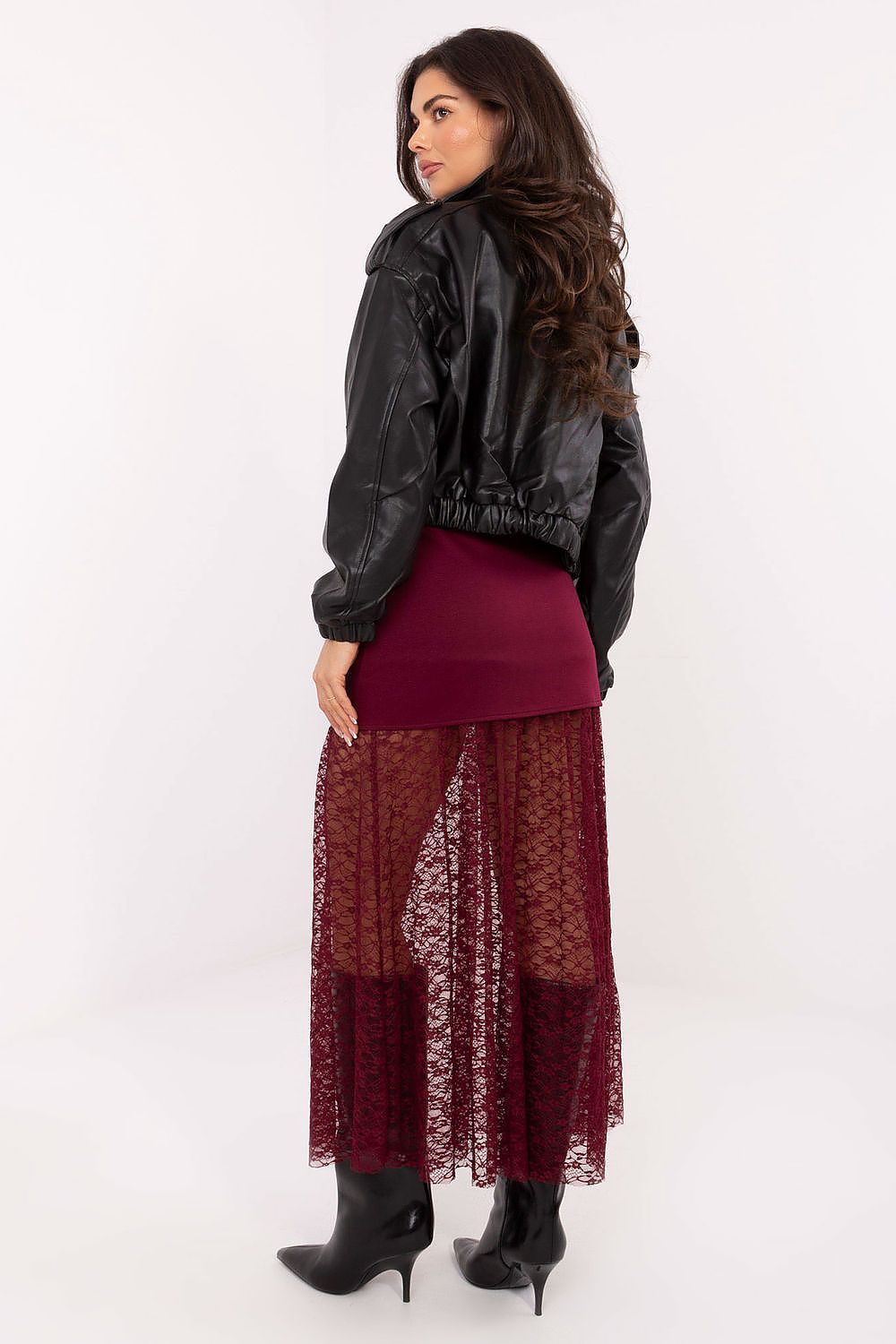 Woman wearing a black leather jacket, burgundy top, and lace skirt on a white background