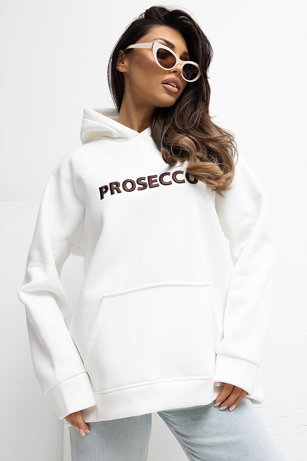 Woman wearing a white hoodie with 'PROSECCO' text on a plain background