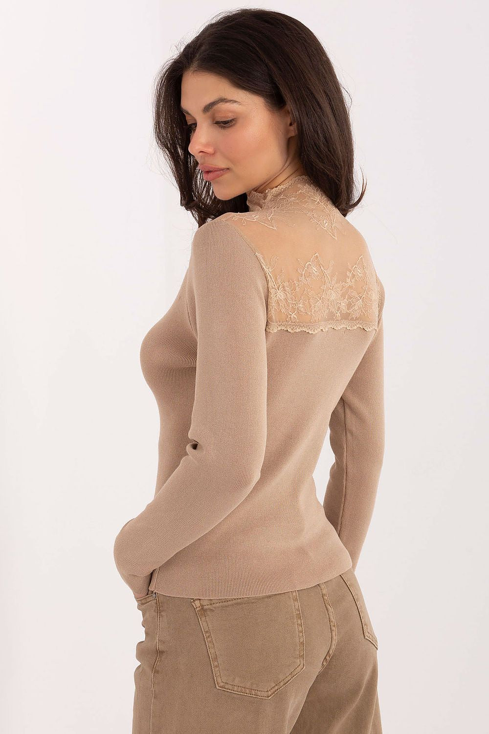 Woman wearing a beige long-sleeve top with lace detailing on a white background
