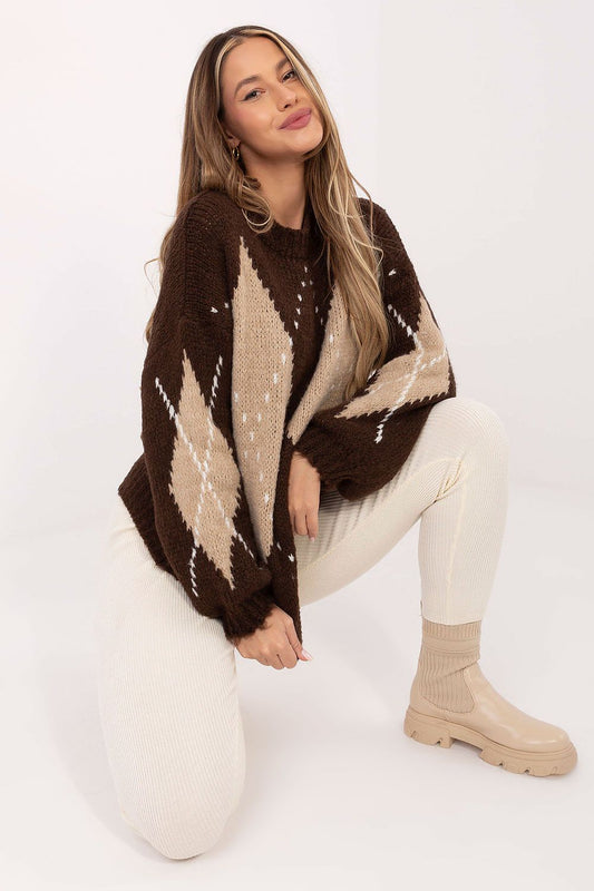 Woman wearing a brown and beige patterned poncho sitting on a white surface.