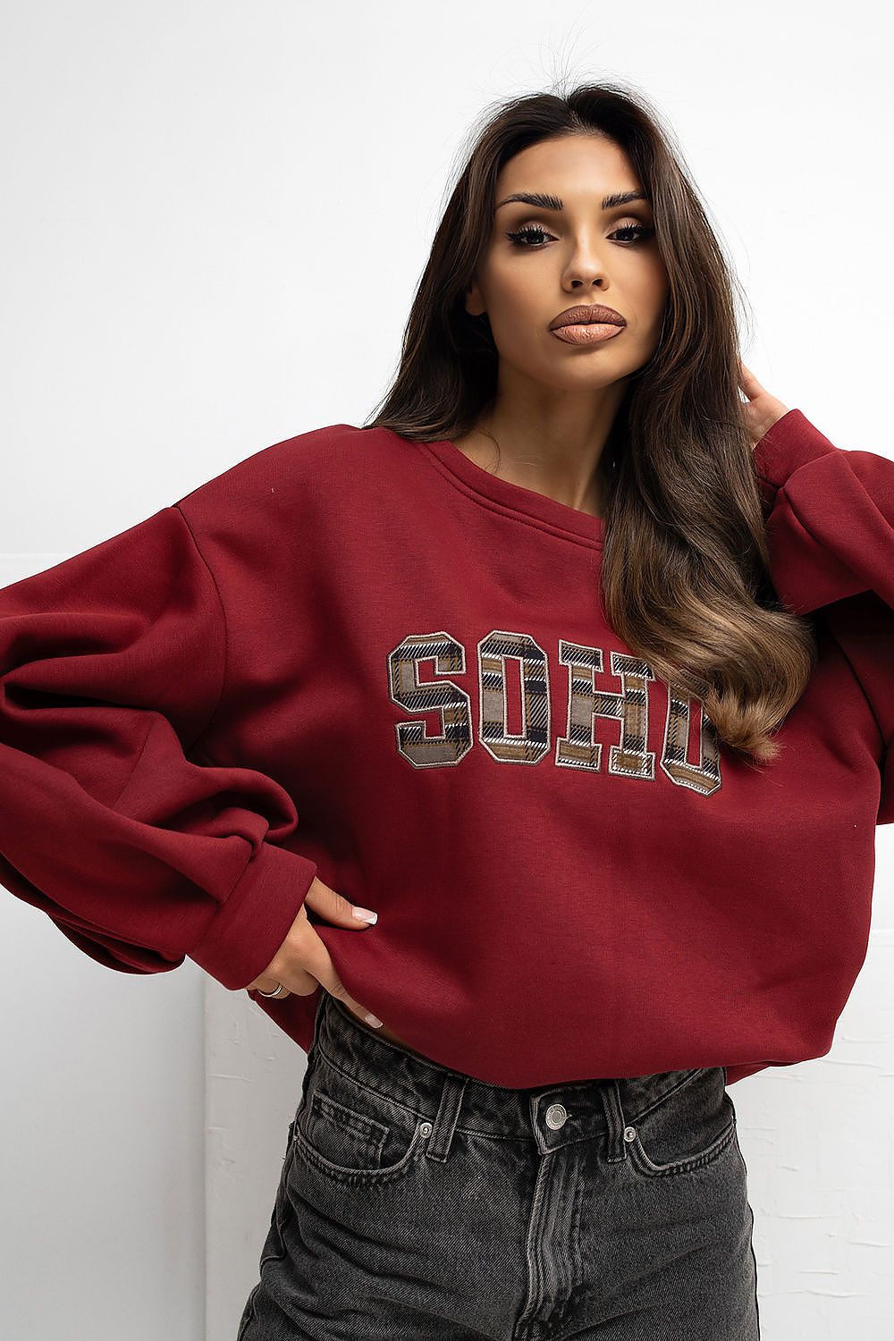 Woman wearing a red sweatshirt with 'SOPH' text against a white background