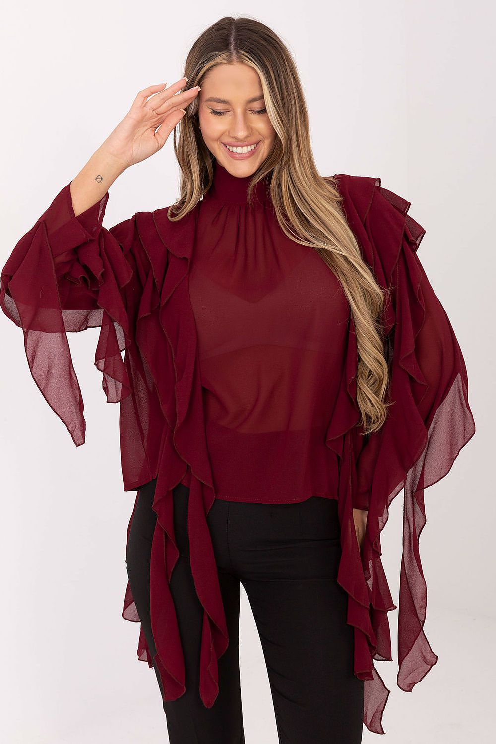 Woman wearing a burgundy top with a sheer red scarf on a white background