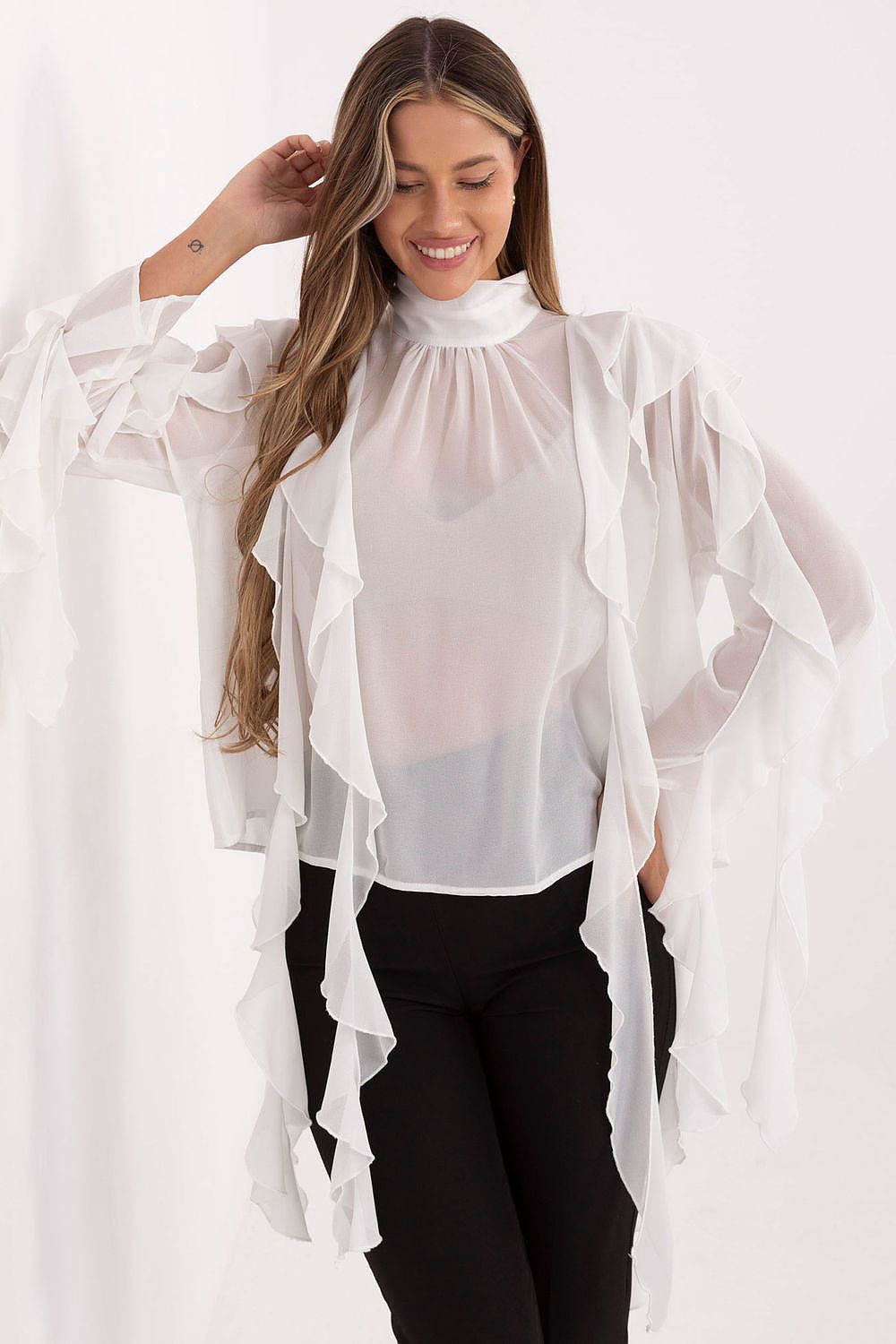 Woman wearing a sheer white blouse over a black top on a white background