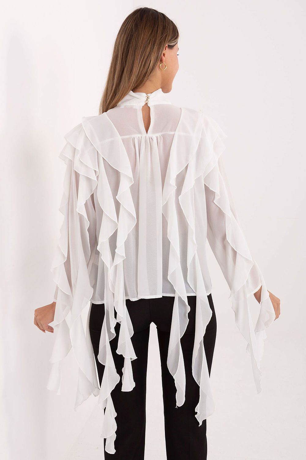 Woman wearing a white ruffled blouse with a plain background