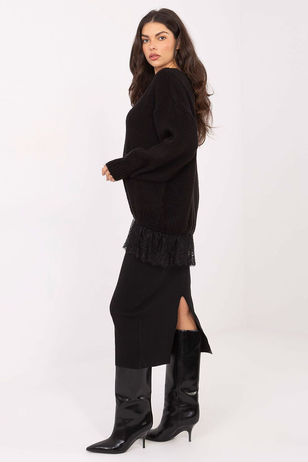 Woman wearing a black dress with ruffled details and black high-heeled boots on a white background