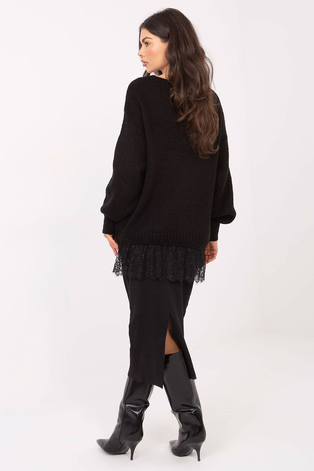 Woman wearing a black dress with lace details and high-heeled boots on a white background