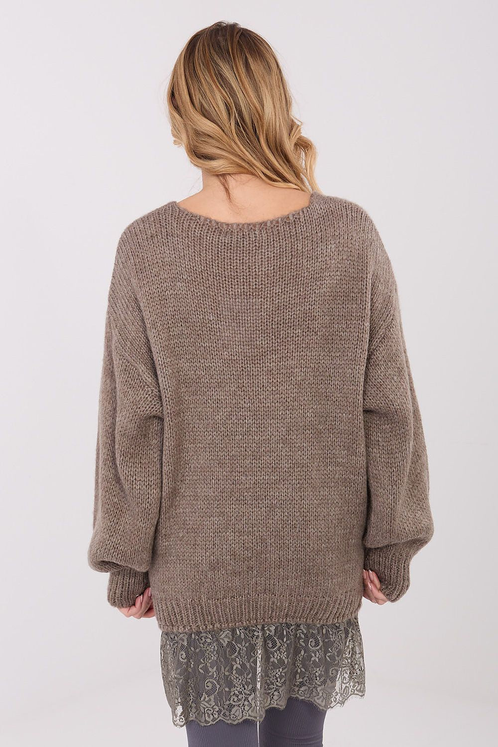 Person wearing a brown knitted sweater with a lace hem on a white background