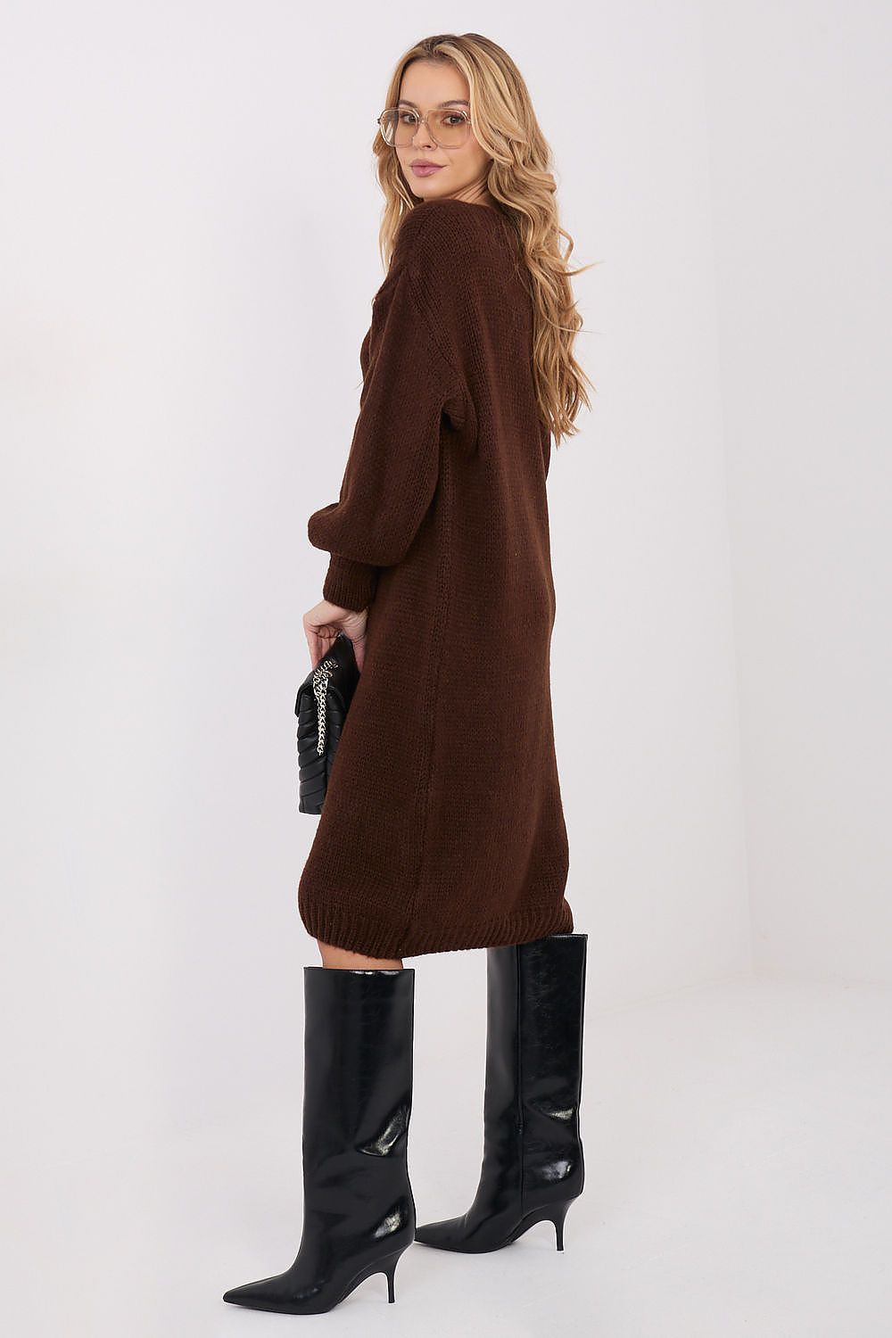 Woman wearing a brown dress and black boots on a white background