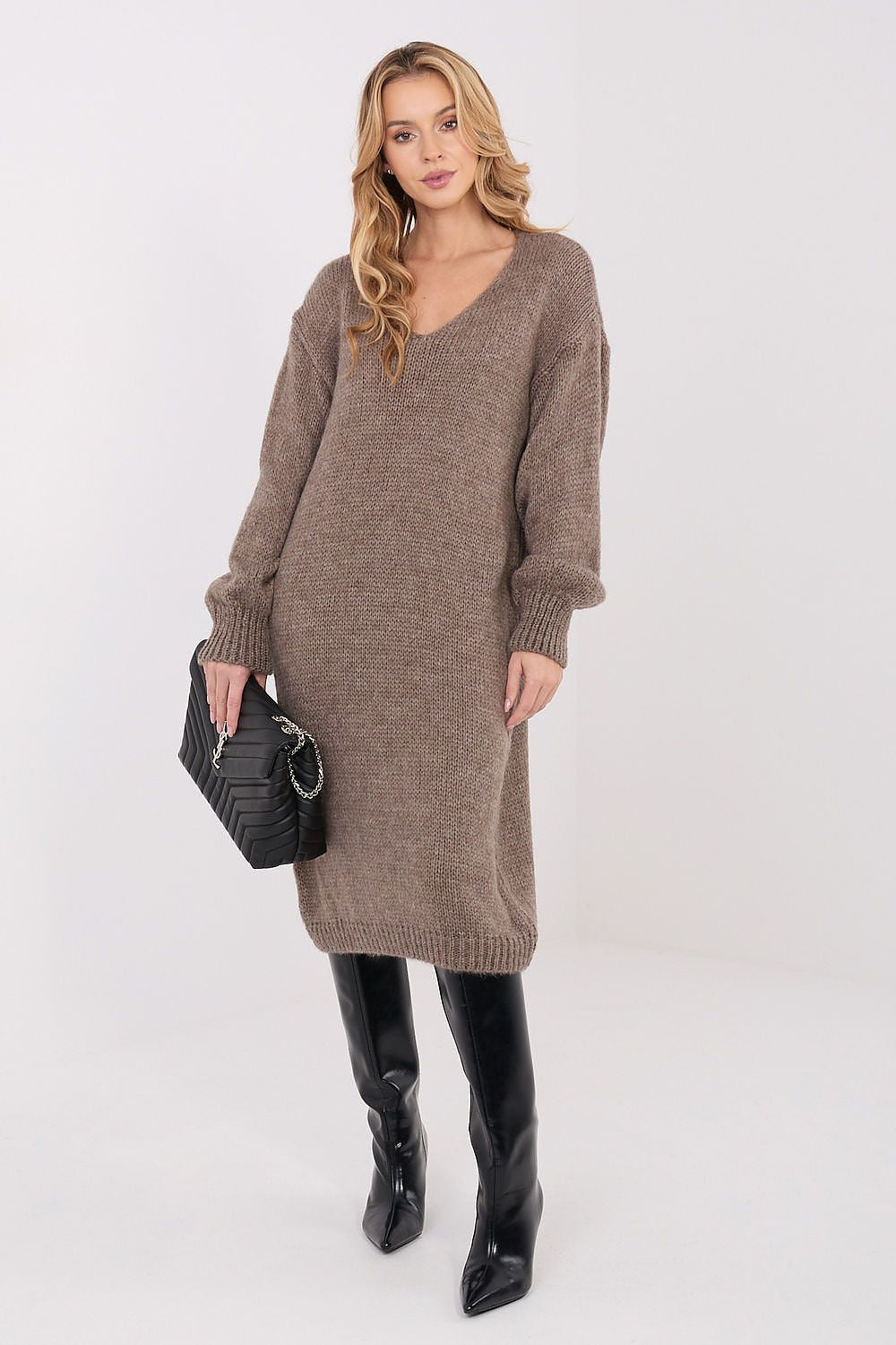 Woman wearing a brown sweater dress and black boots on a white background