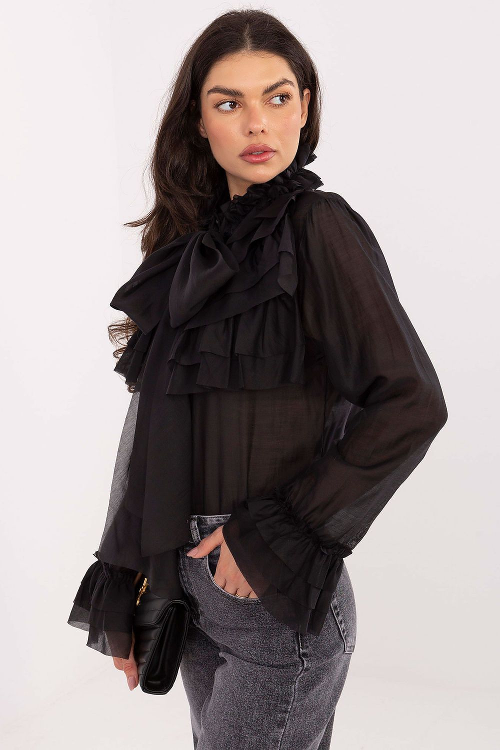 Woman wearing a black ruffled blouse with sheer sleeves on a white background