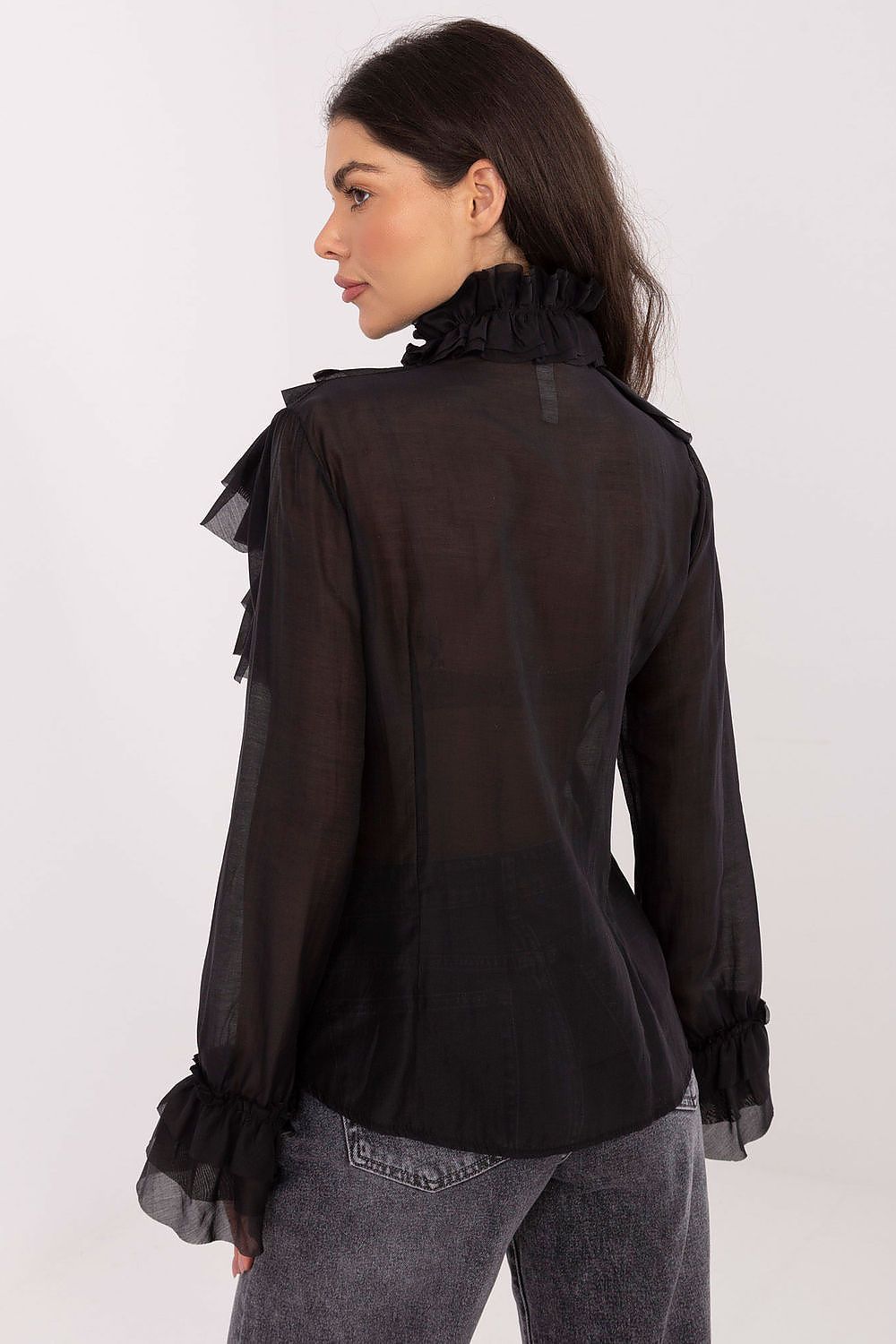 Woman wearing a black blouse with ruffled details on a white background