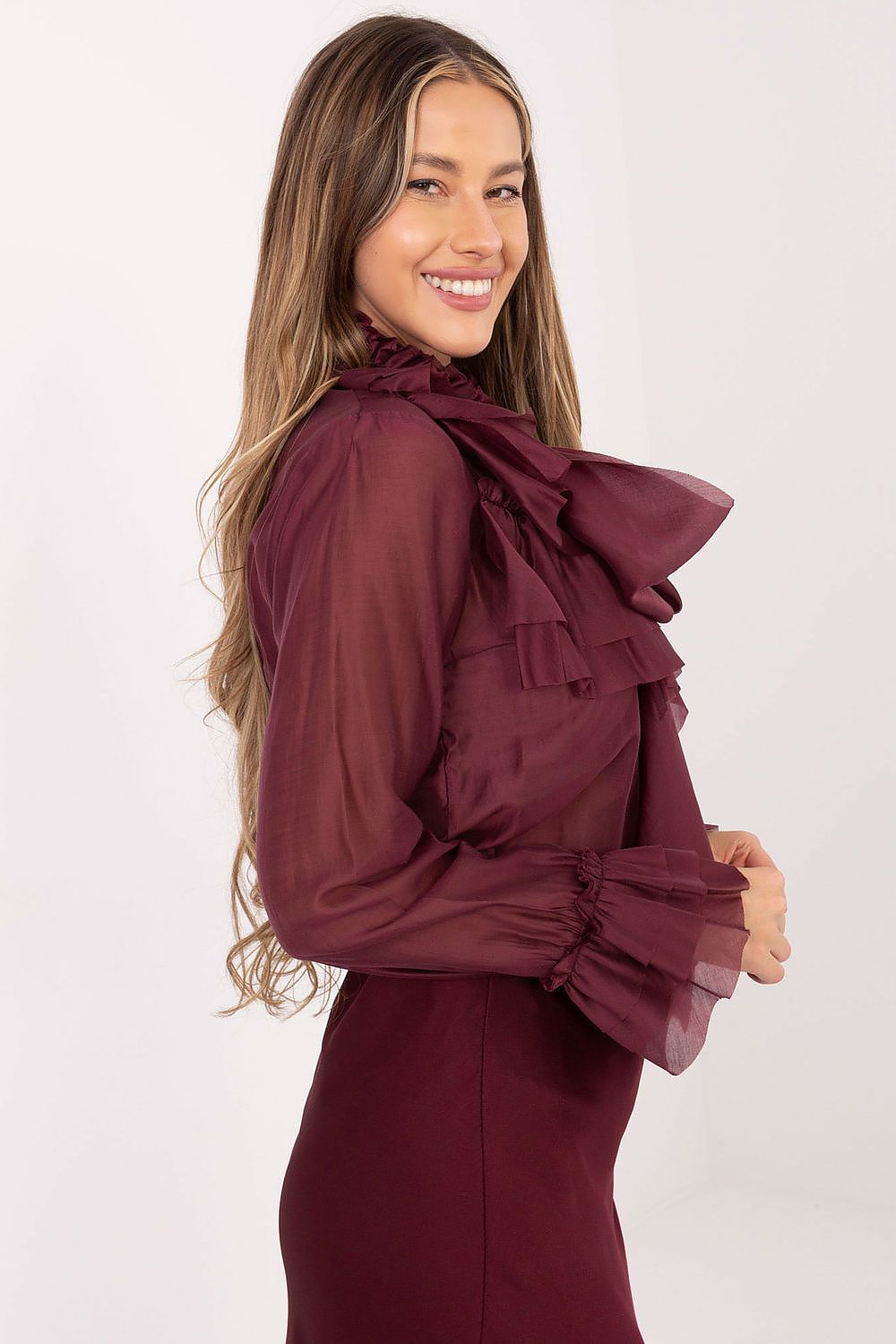 Woman wearing a burgundy dress with ruffled details on a white background