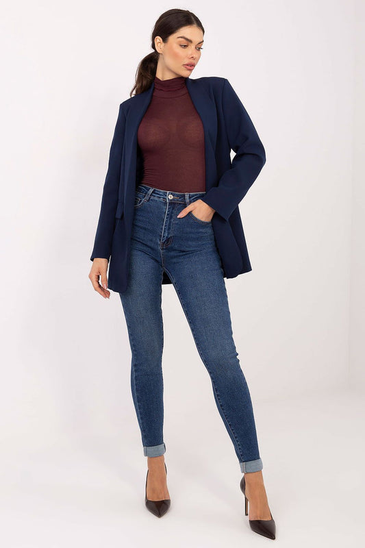 Woman wearing a navy blazer, maroon top, and blue jeans on a white background