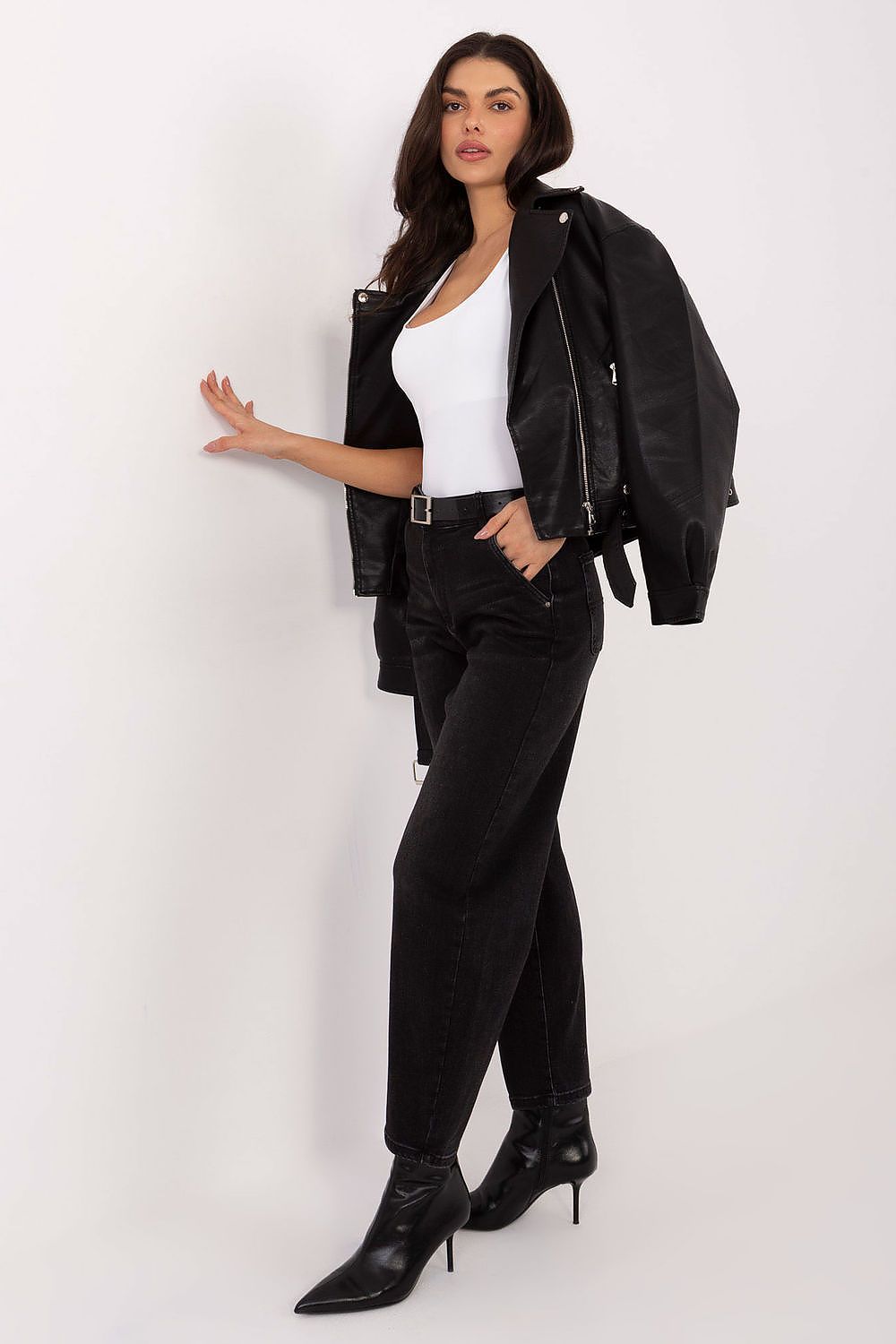 Woman wearing a black jacket, white top, black pants, and black boots on a white background