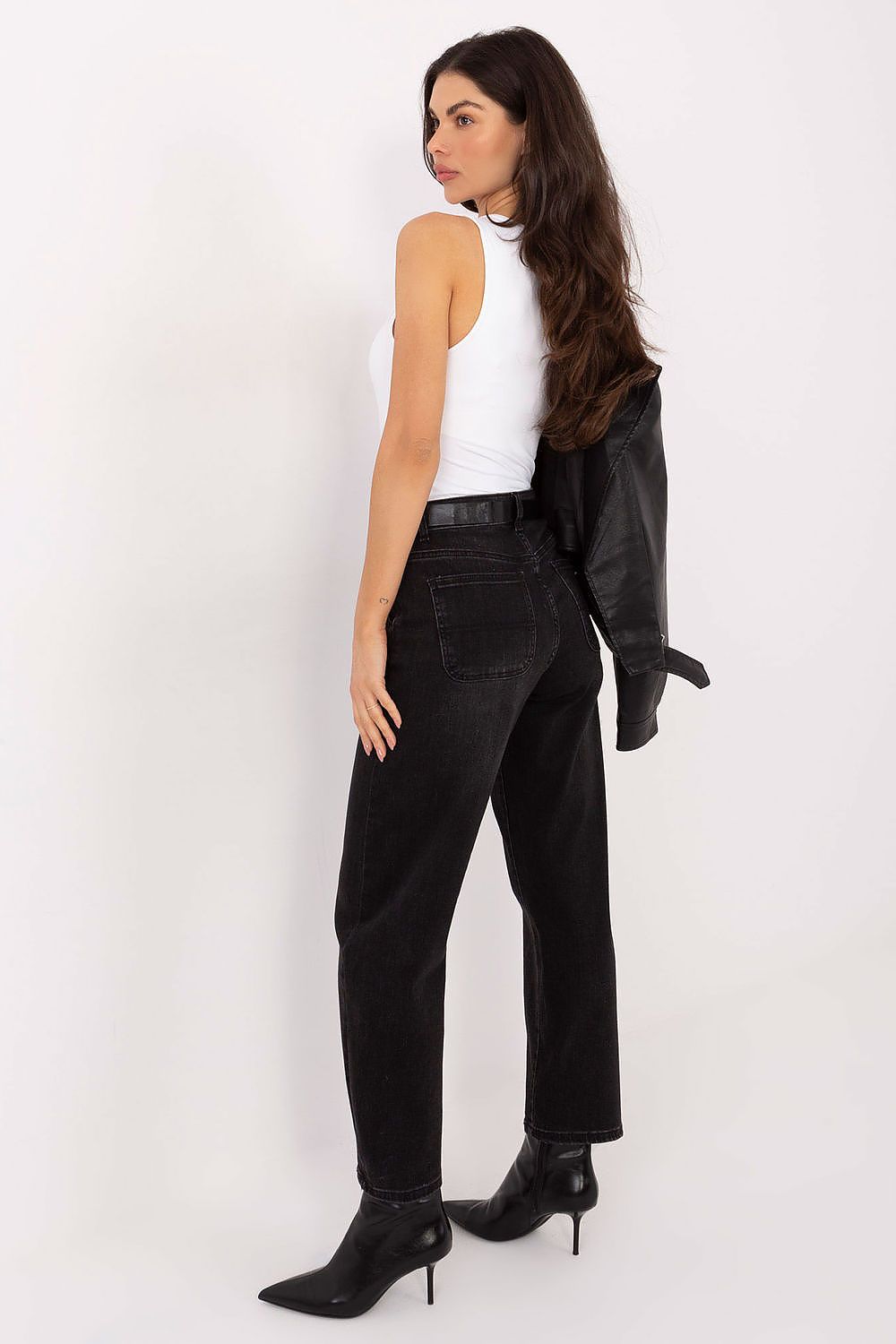 Woman wearing black high-waisted jeans and a white top on a white background
