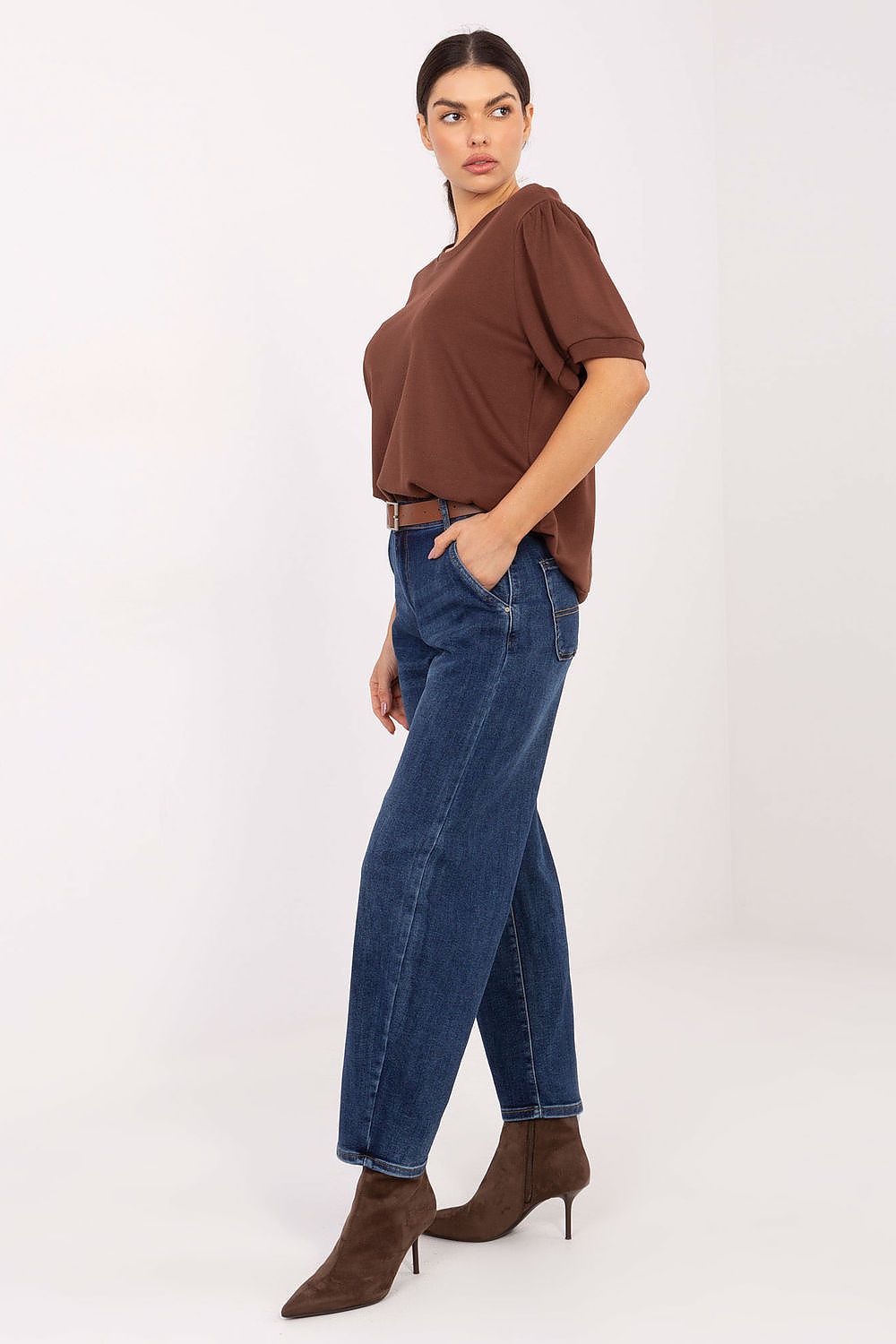 Woman wearing a brown top and blue jeans on a white background
