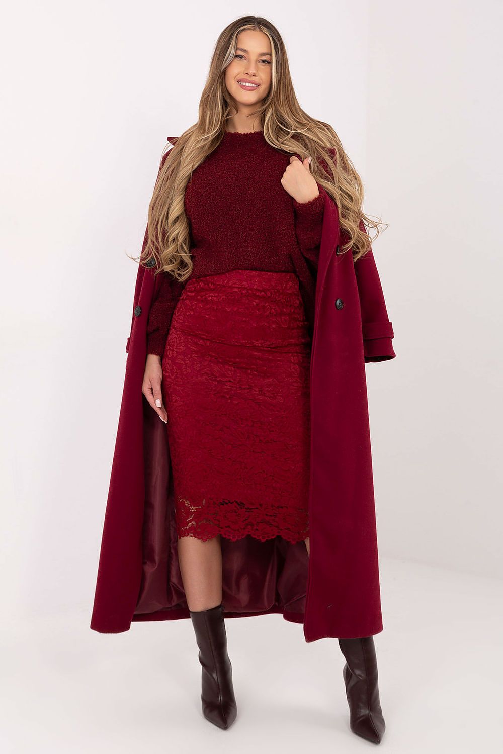 Woman wearing a burgundy outfit with a long coat on a white background