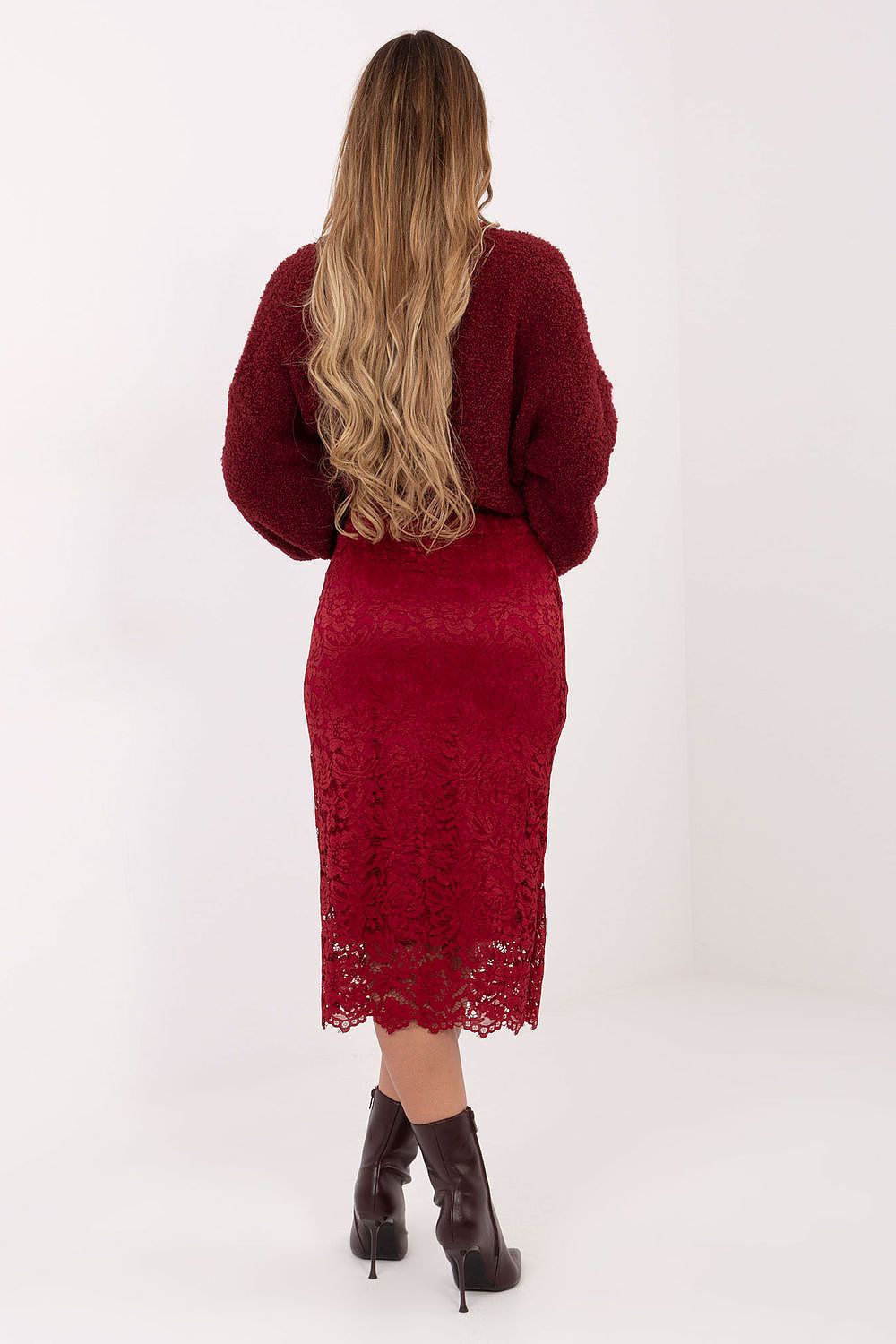 Person wearing a red lace dress and matching cardigan on a white background
