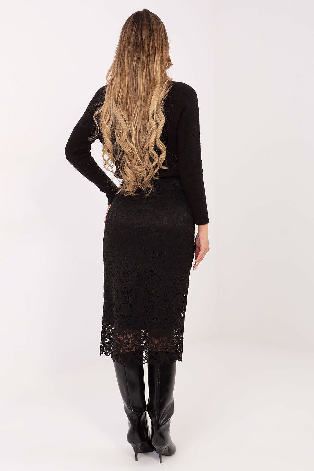 Woman wearing a black lace dress with a plain white background