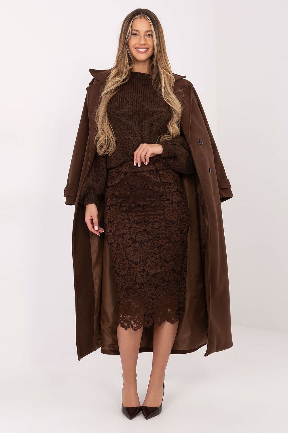 Woman wearing a brown coat, sweater, and lace skirt on a white background