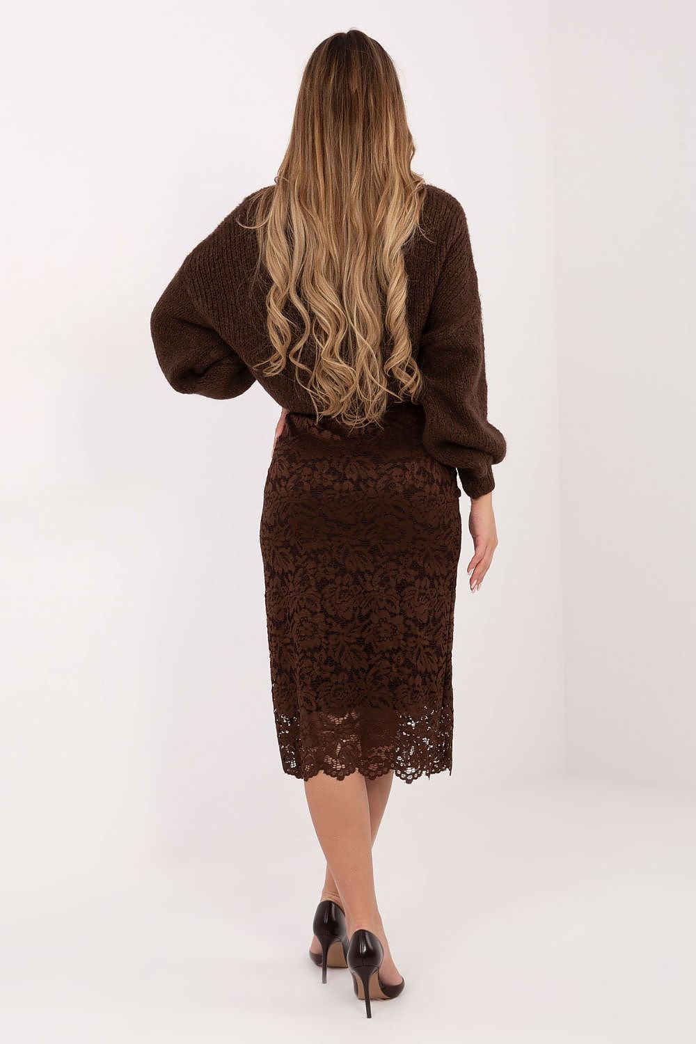 Woman wearing a brown lace dress and cardigan set on a white background