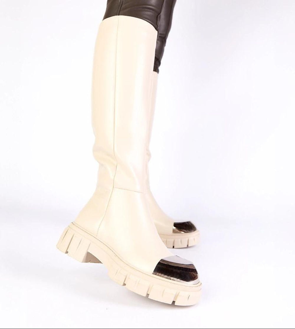 White knee-high boots with black soles on a white background