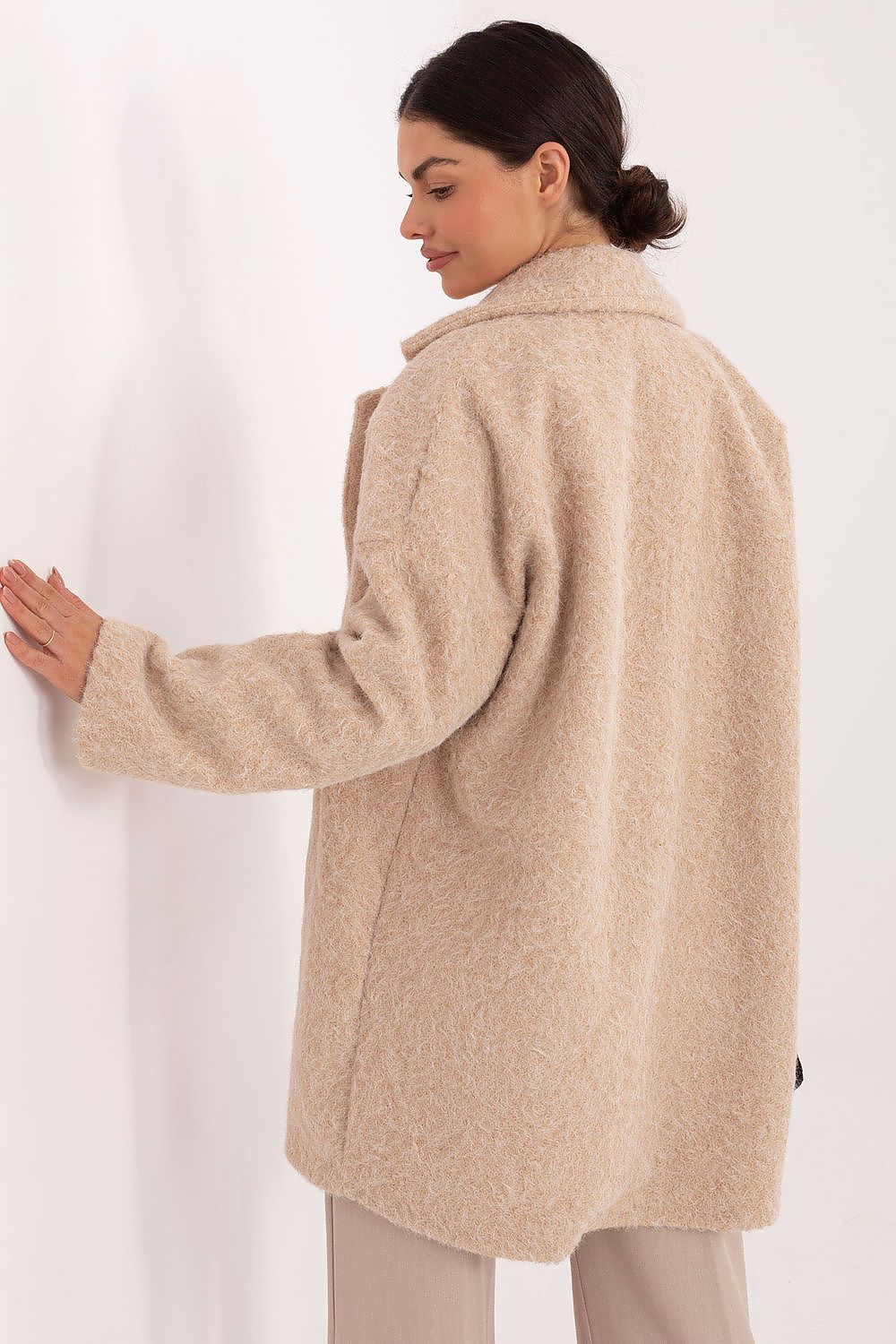 Woman wearing a beige coat against a white background