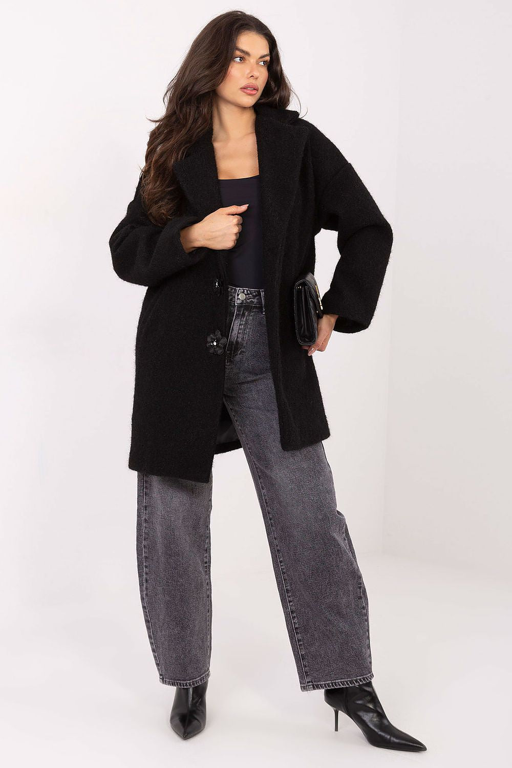 Woman wearing a black coat and gray jeans on a white background