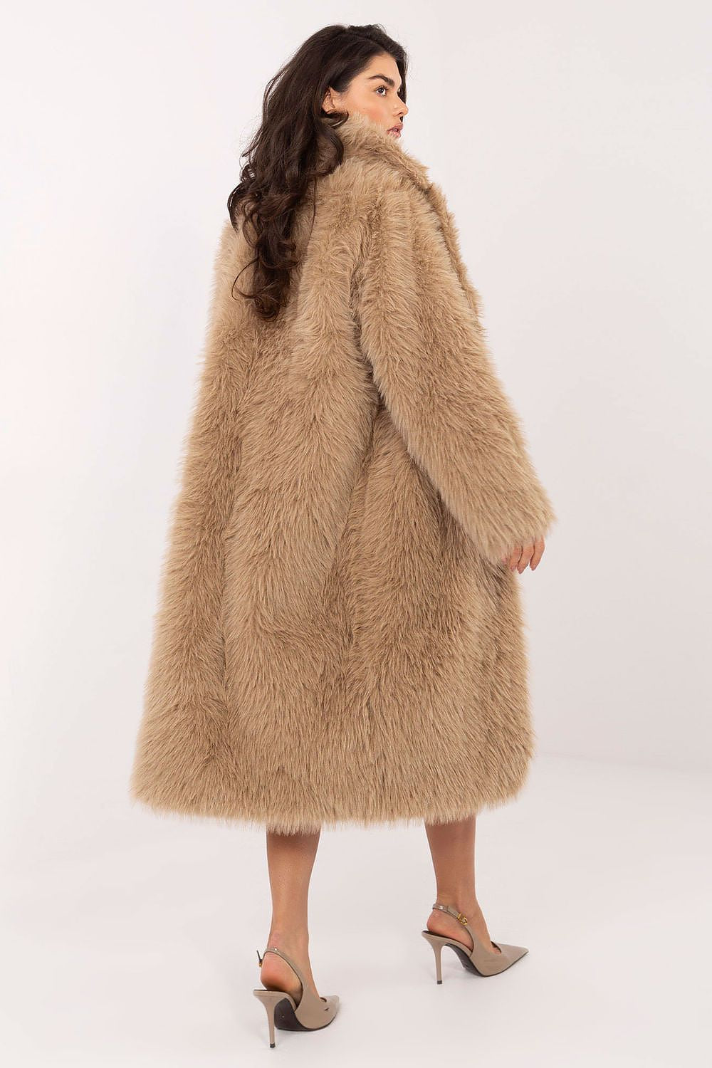 Woman wearing a long beige fur coat on a white background