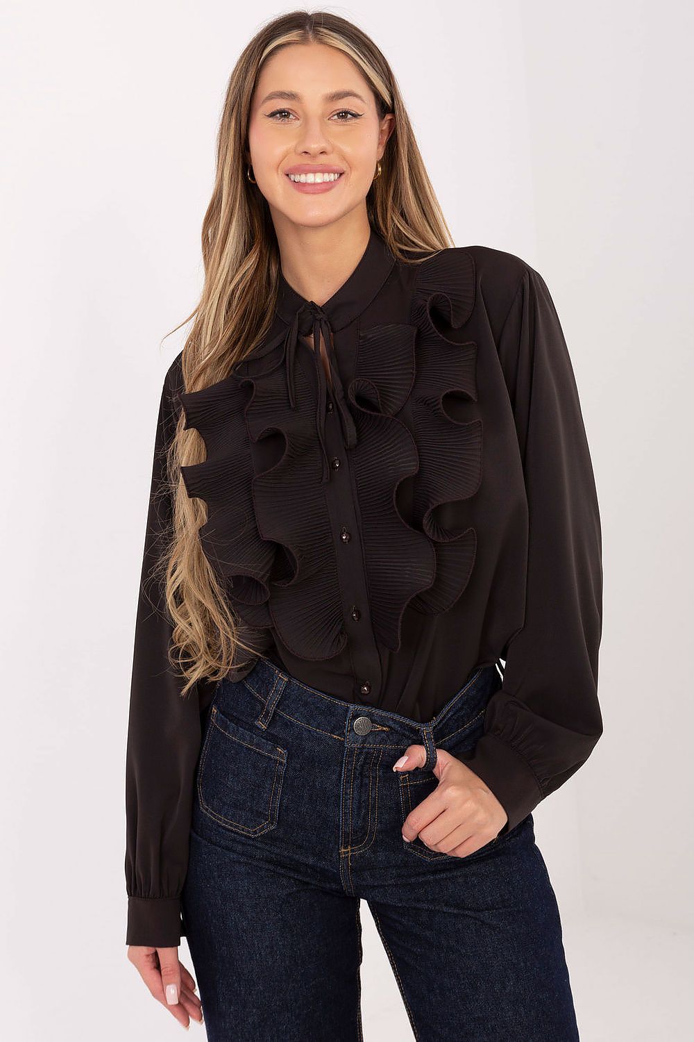 Woman wearing a black ruffled blouse and blue jeans on a white background