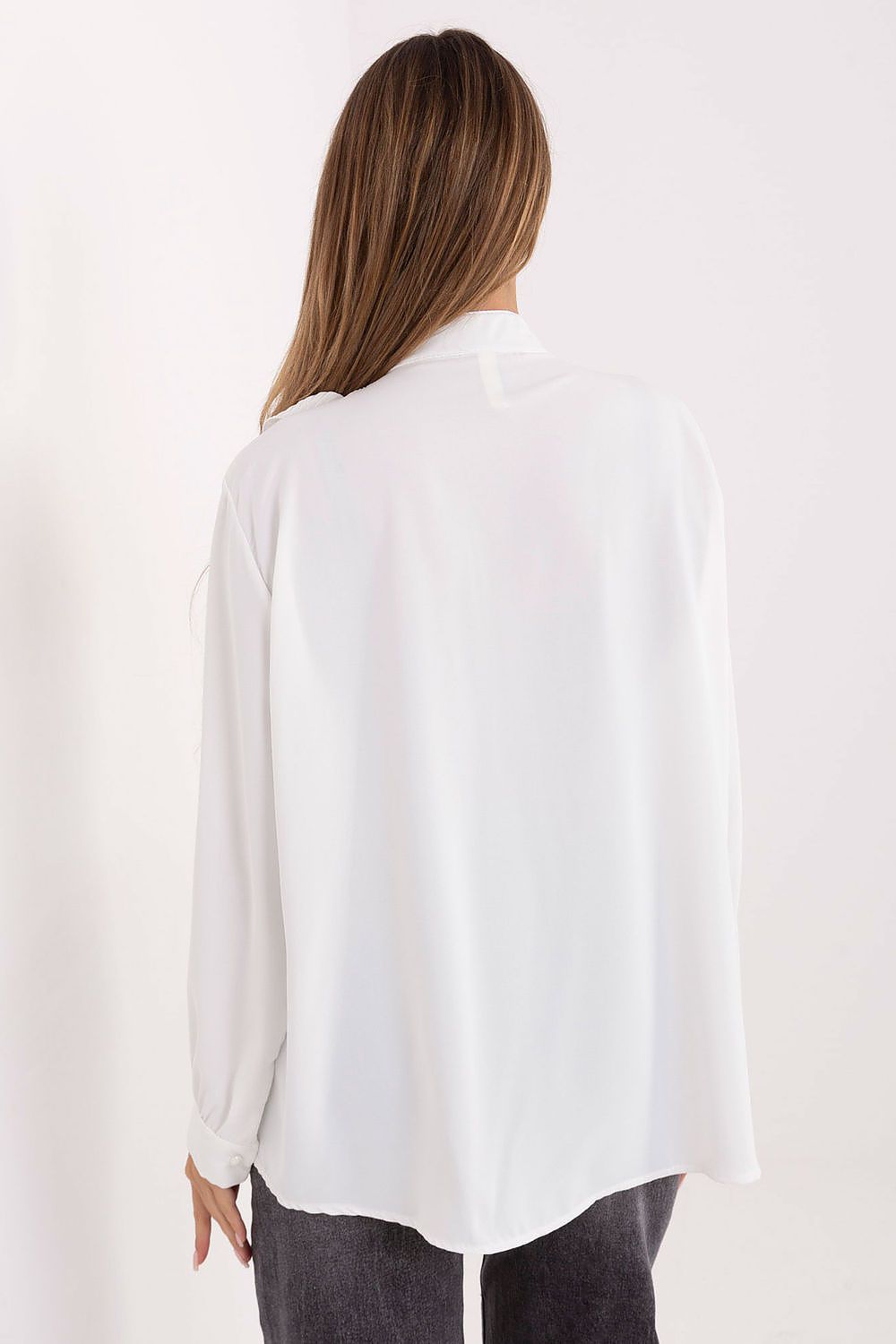 Person wearing a white blouse with long sleeves on a plain background