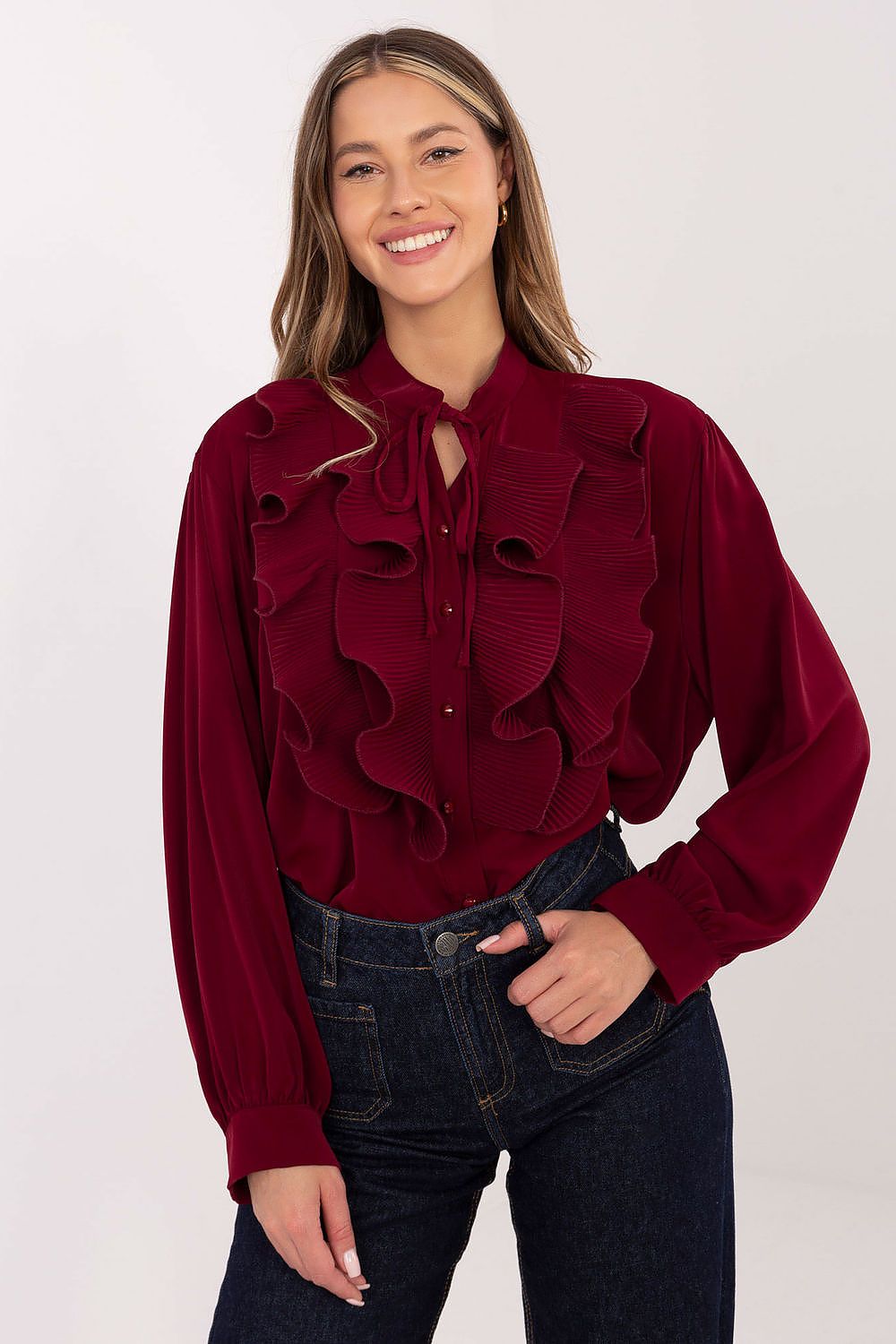 Woman wearing a burgundy ruffled blouse against a white background