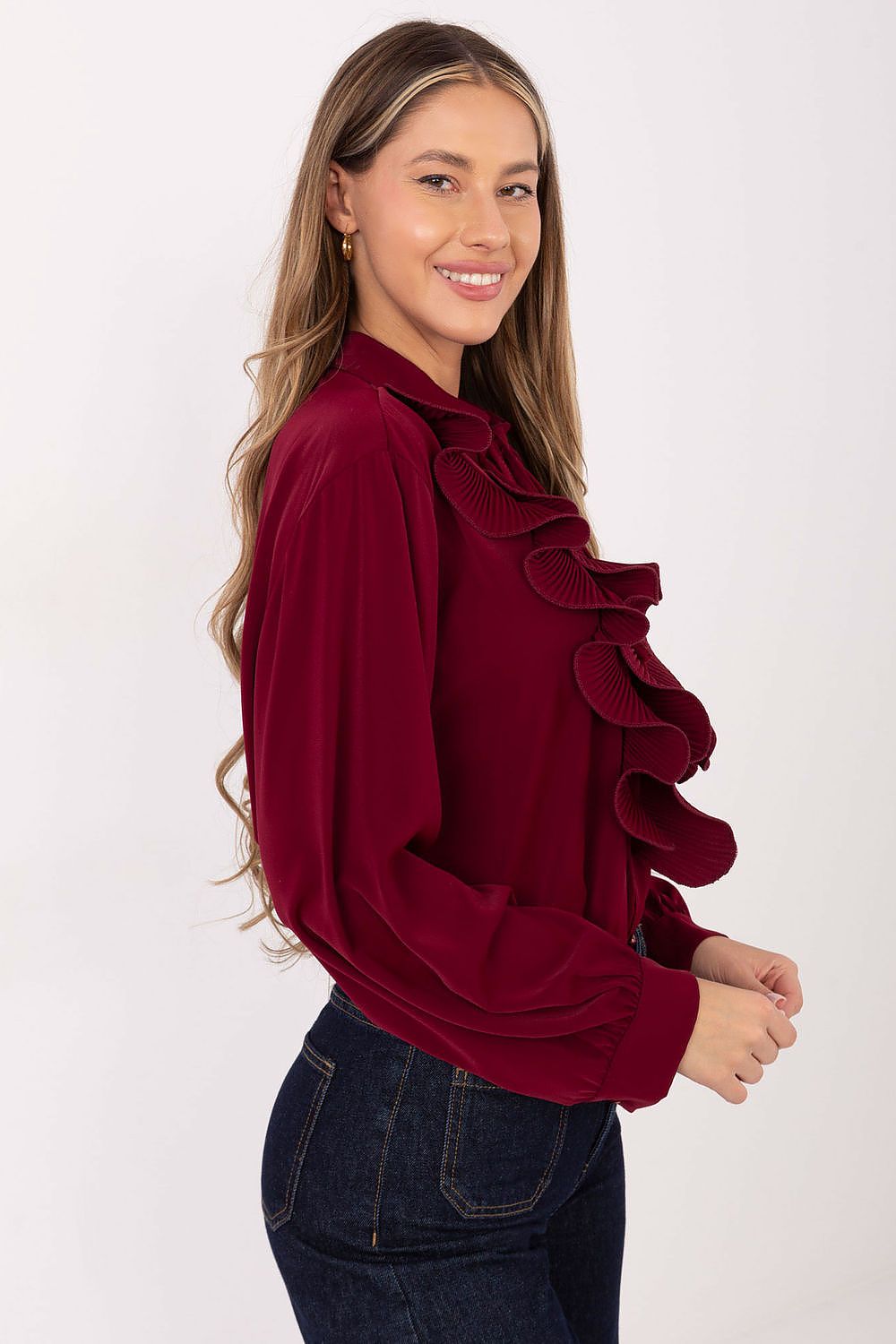 Woman wearing a burgundy blouse with ruffled details on a white background