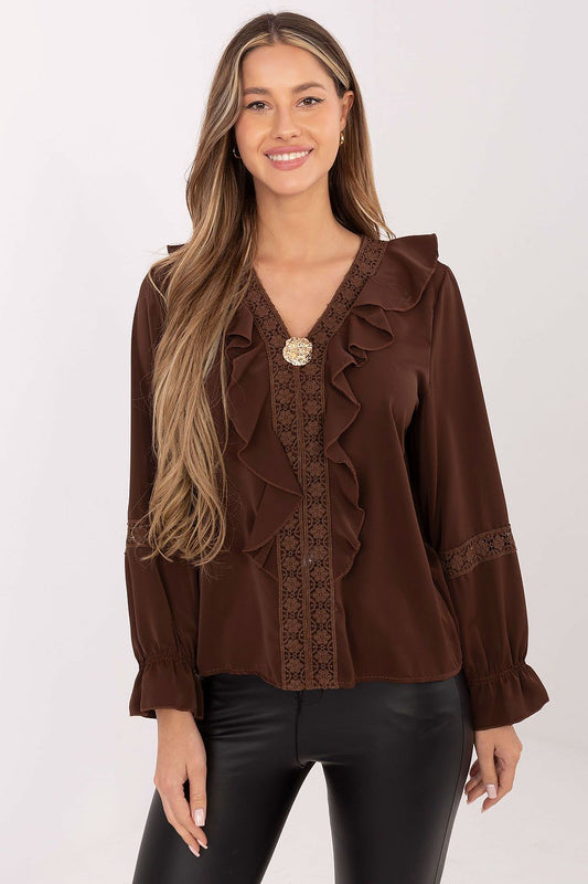 Woman wearing a brown blouse with ruffled details on a white background