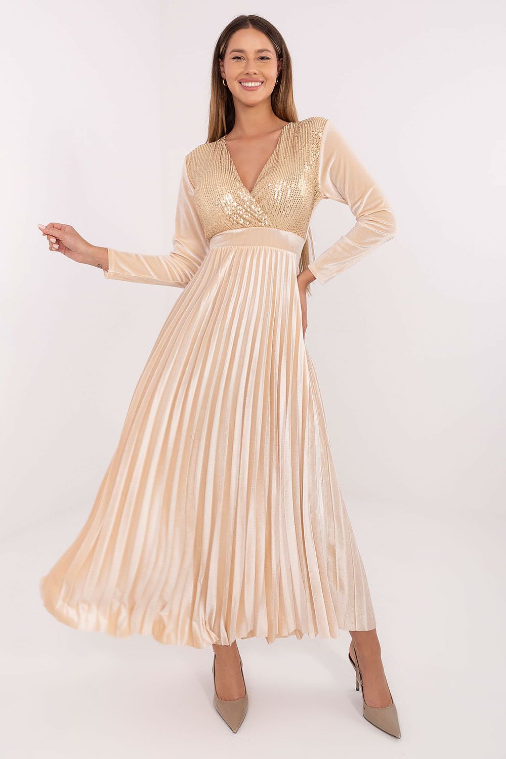 Woman wearing a beige pleated dress with long sleeves on a white background