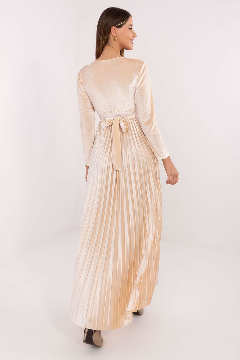 Woman wearing a long, light-colored dress with a belt on a white background