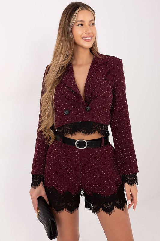 Woman wearing a burgundy polka dot outfit with lace details on a white background