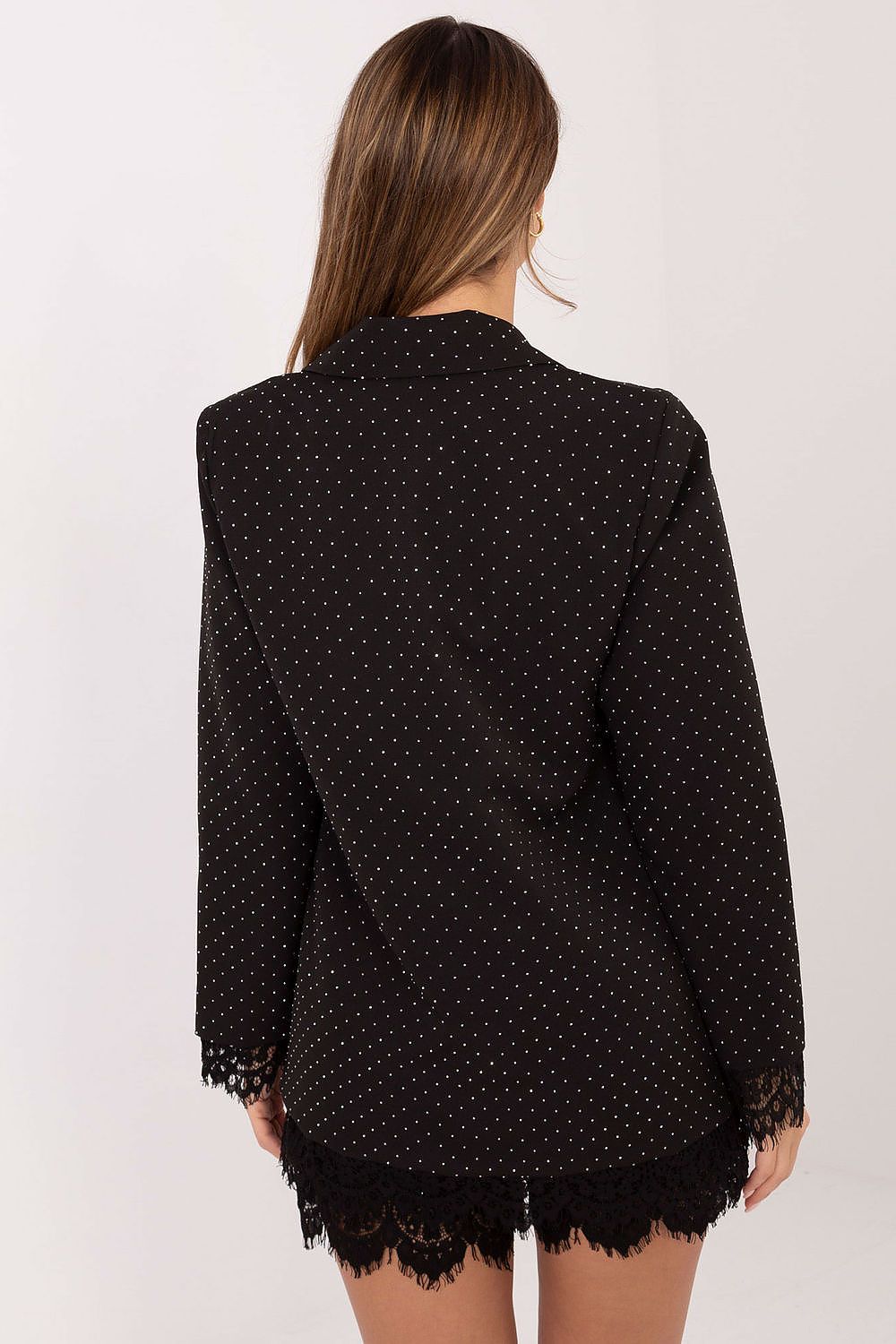 Woman wearing a black polka dot blouse with lace trim on a white background