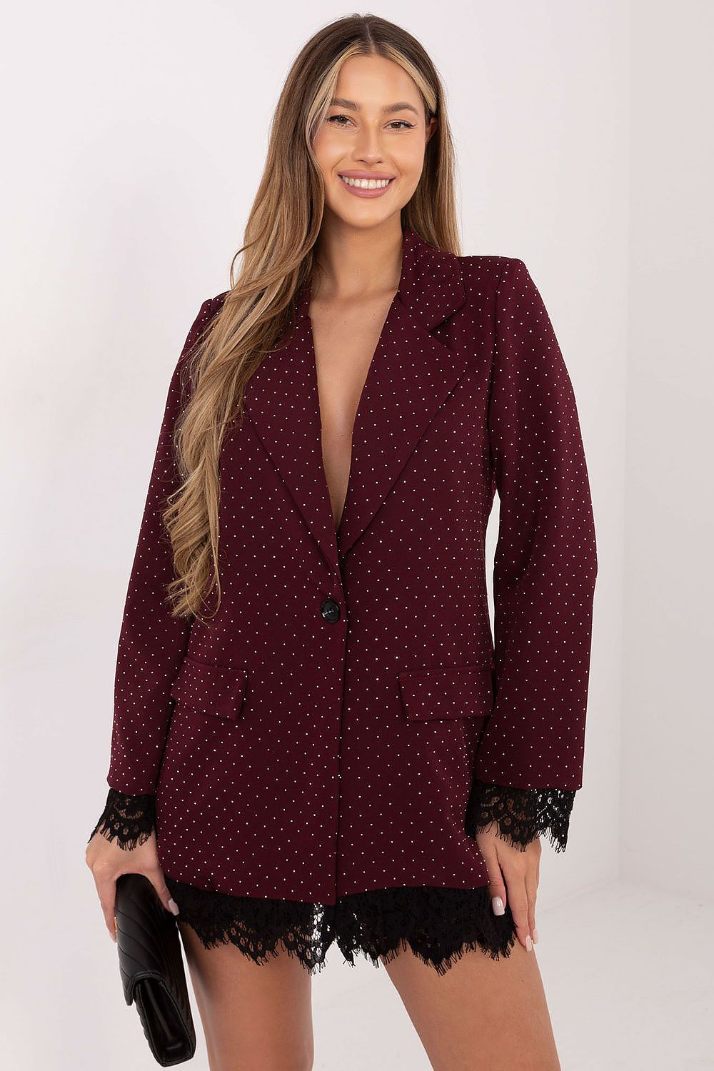 Woman wearing a burgundy blazer with lace trim on a white background
